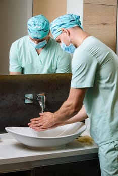 Medical student is washing his hands under running water. Hygiene for doctors. Good method to stop pandemic of coronavirus covid-19