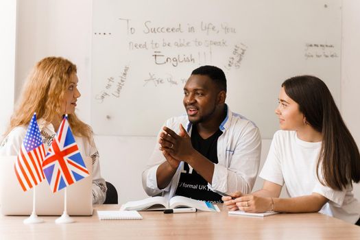 Attractive friendly-looking colleagues are working together in an office, discussing something on white background.