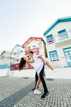 Young couple stays in tango pose and looks each others in Aveiro, Portugal near colourful and peaceful houses. Lifestyle. Having fun