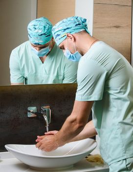 Surgeon cleans his hands with antiseptic before surgery. wash hands often to stop pandemic of coronavirus covid 19