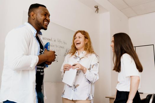 Multiethnic happy students and black teacher study foreign languages and smile and laught together in class. Studing with laptop.