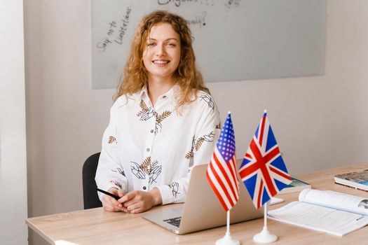 Close-up portrait of a beautiful smiling student on bright background. Happy ginger female teacher smiling to her colleagues