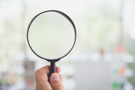Magnifying glass with blur indoor home background.