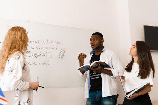 Attractive friendly-looking colleagues are working together in an office, discussing something on white background