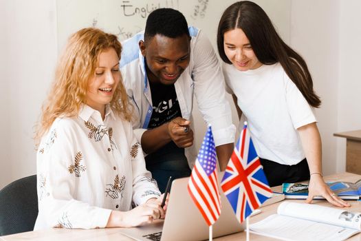 Multiethnic happy students and black teacher study foreign languages and smile and laught together in class. Studing with laptop.