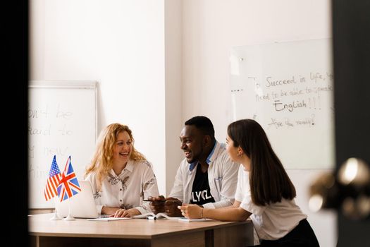 Online multiethnic attractive group of teachers study and laught, discuss something. Remote work in multinational group with laptop.