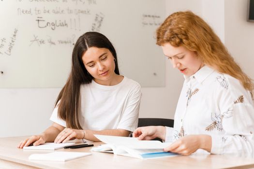 Teacher of english asks student in white class. 2 girls student answers to teacher. Working in group. Study english and british language.