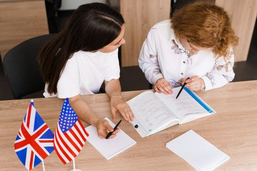 Teacher of english asks student in white class. 2 girls student answers to teacher. Working in group. Study english and british language.