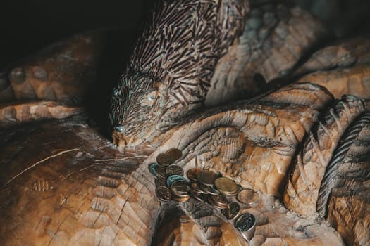 Old coins lie on a wooden carved figure. High quality photo