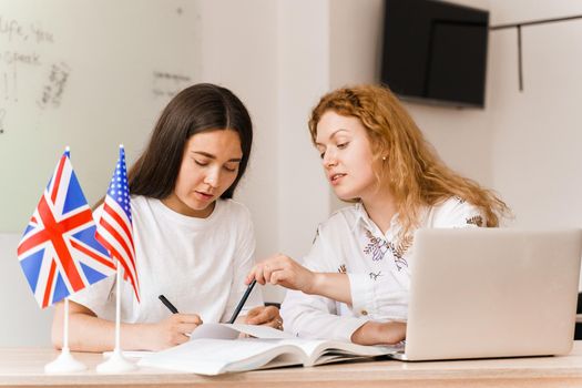 Foreign school private study with a school girl. Teacher explain grammar of native language using laptop. Prepearing to exam with tutor.