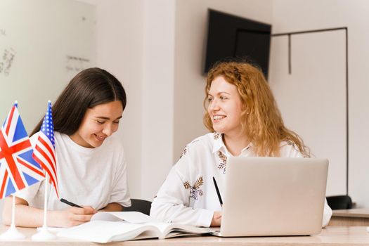 Foreign school private study with a school girl. Teacher explain grammar of native language using laptop. Prepearing to exam with tutor.