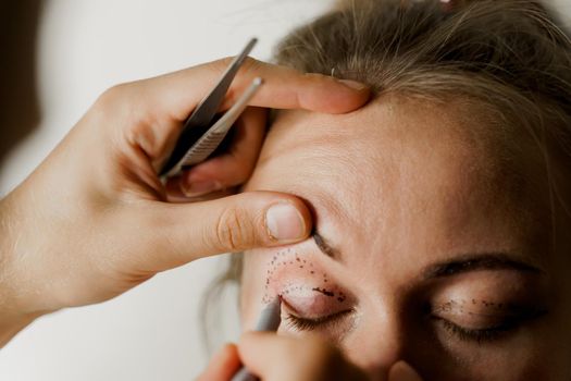 Blepharoplasty markup close-up on the face before the plastic surgery operation for modifying the eye region of the face in medical clinic. 2 doctors do plastic cosmetic operation