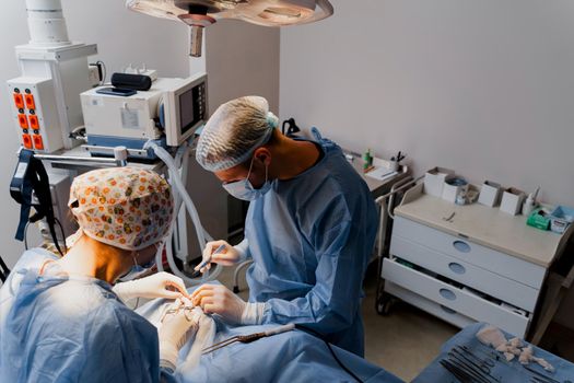 Blepharoplasty plastic surgery operation for modifying the eye region of the face in medical clinic. Surgeon makes an incision with a surgical knife