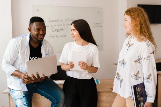 Multiethnic students and teacher study foreign languages together in class. Studing with laptop. Black handsome student study with white people together.