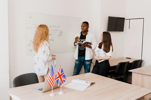 Multiethnic students and teacher study foreign languages together in class. Studing with laptop. Black handsome student study with white people together.