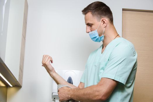 Surgeon washes his hands in medical clinic before operation. Covid 19 virus stop.