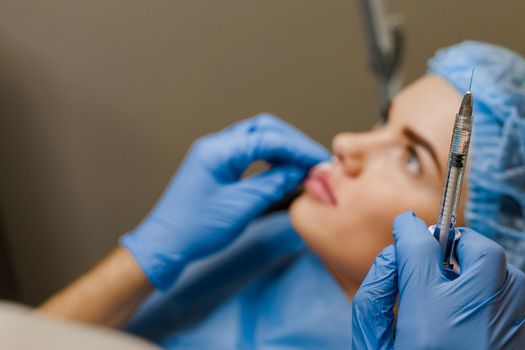Lips augmentation injections for attractive girl. Plastic surgeon does injection in lip in medical clinic. Cosmetic rejuvenating facial treatment