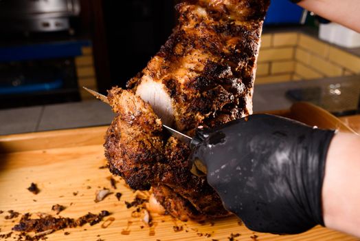 Fried pork cut with a knife. Big peace of pork meat. Cutting meat. Chef cut pork with knife. Advert for meat menu for restaurant