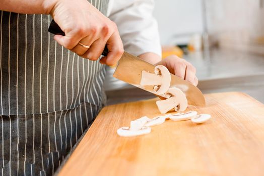 Cut white mushrooms for ramen soup on kitchen . Chef cooks white mushrooms with knife in restaurant. Cutting white mushrooms