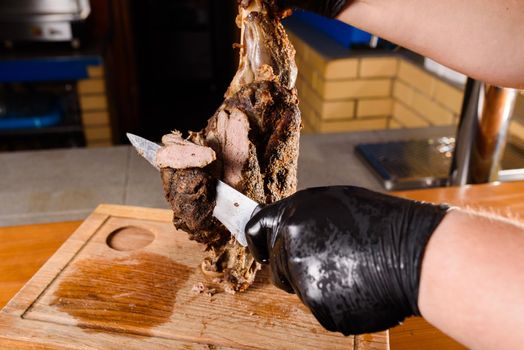 Fried pork cut with a knife. Big peace of pork meat. Cutting meat. Chef cut pork with knife. Advert for meat menu for restaurant