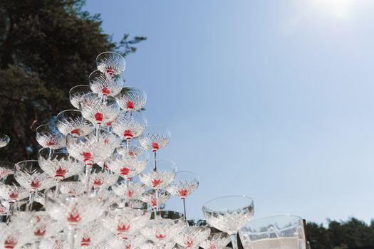 Wine glasses in pyramid of champagne close-up. Drink catering for wedding ceremony. Alcohol cocktails for guests. Business meeting open air