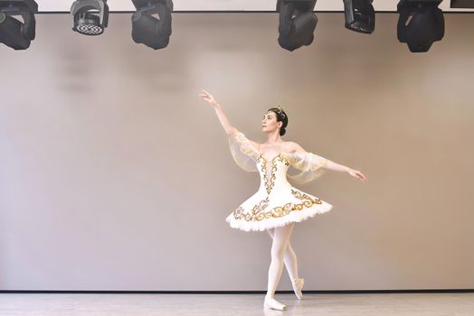 young beautiful woman ballet dancer in a white tutu practicing classical dance steps in studio before performance