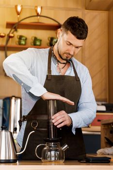 Aeropress coffee: barista press to device and coffee drops pours trought aeropress to pot. Alternative coffee brewing method
