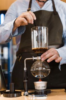 Coffee brewing by Syphon device. Close up syphon is heating by fire. Brewing photo on the fire. Alternative method of coffee making.