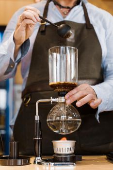 Coffee brewing by Syphon device. Close up syphon is heating by fire. Brewing photo on the fire. Alternative method of coffee making.