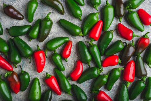 Red, Green and Brown Jalapeno Chili Peppers on Light Concrete Background. View from Above