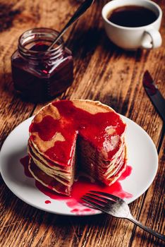 Stack of pancakes with berry fruit marmalade on plate over wooden surface