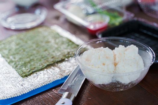 Cocking sushi rolls recipe with nori, rice, salmon, cucumber, and cheese. Tasty japanese food. Preparations ingredients for sushi on the table
