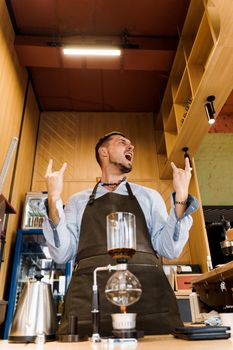 Syphon coffee device with fire heats glass flask in cafe. Emotional barista shows rock and roll. Alternative coffee brewing method