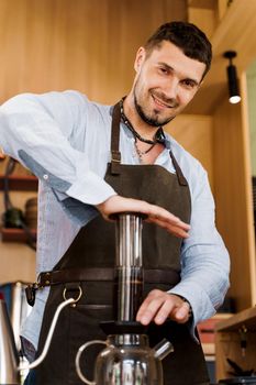 Aeropress coffee: barista press to device and coffee drops pours trought aeropress to pot. Alternative coffee brewing method