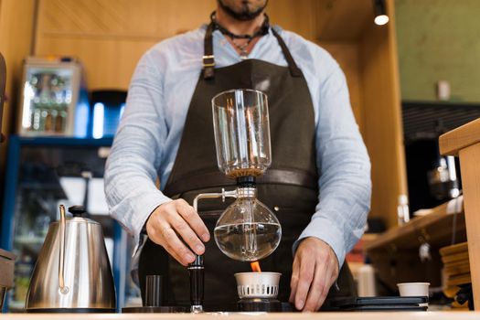Coffee brewing by Syphon device. Syphon is heating by fire. Brewing photo on the fire. Alternative method of coffee making.