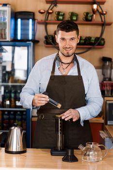 Aeropress coffee and handsome bearded barista in cafe. Barisa cook tasty coffee using alternative brewing method