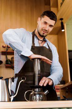 Aeropress coffee: barista press to device and coffee drops pours trought aeropress to pot. Alternative coffee brewing method