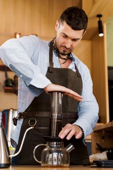 Aeropress coffee: barista press to device and coffee drops pours trought aeropress to pot. Alternative coffee brewing method