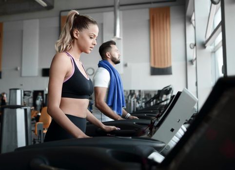 beautiful sports people work on the treadmill in the gym . healthy lifestyle