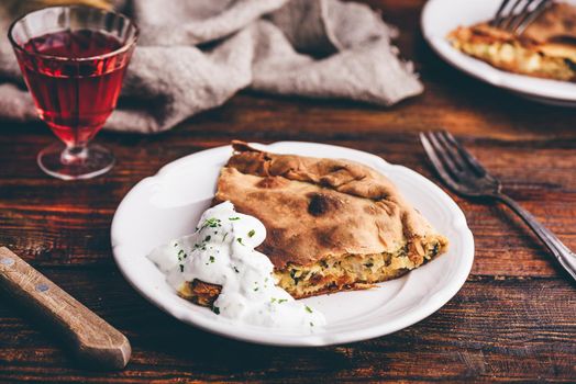 Slice of cabbage pie with sour cream sauce on white plate