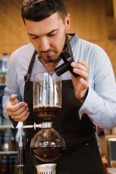 Barista sniffs flavored coffee in syphon device. Coffee brewing syphon alternative method. Advert for social networks for cafe and restaurant.
