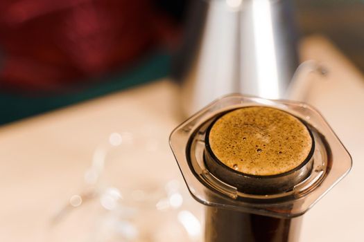 Coffee aeropress creams close-up. Alternative coffee brewing method. Aeropress device on the table. Advert for social networks of restaurants, cafe.