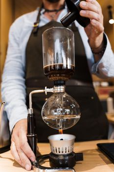 Coffee brewing by Syphon device. Close up syphon is heating by fire. Brewing photo on the fire. Alternative method of coffee making