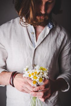 Bearded Man in Linen Shirt with Long Hair Holding Bouquet of Daisy Flowers in Hands