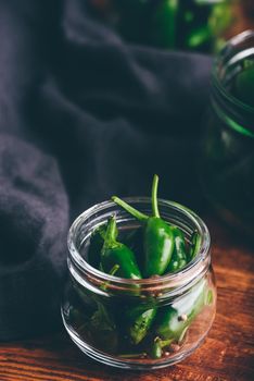 Fresh Jalapeno Peppers in Glass Jars for Canning with Herbs and Garlic on Wooden Table