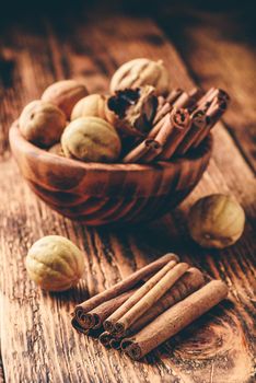 Cinnamon sticks and dried limes in wooden bowl on rustic table