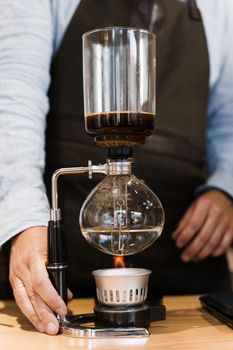 Coffee brewing by Syphon device. Close up syphon is heating by fire. Brewing photo on the fire. Alternative method of coffee making.