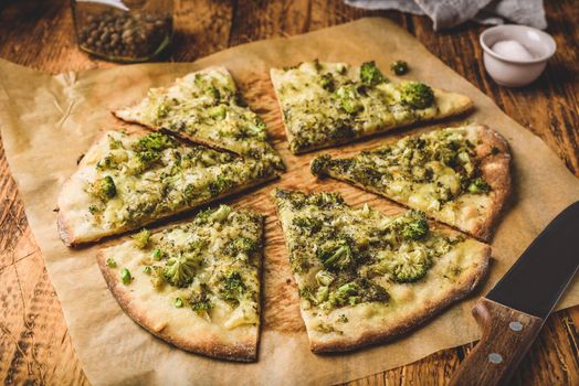 Slices of homemade pizza with broccoli and cheese on baking paper