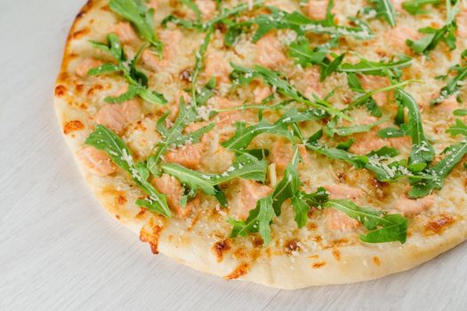 Pizza with salmon, parmesan and arugula isolated on white wooden background. Advert for social network of restaurants, caffee. Promotion for pizzeria.