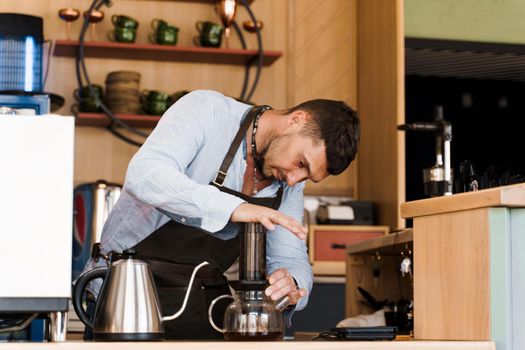 Aeropress coffee: barista press to device and coffee drops pours trought aeropress to pot. Alternative coffee brewing method